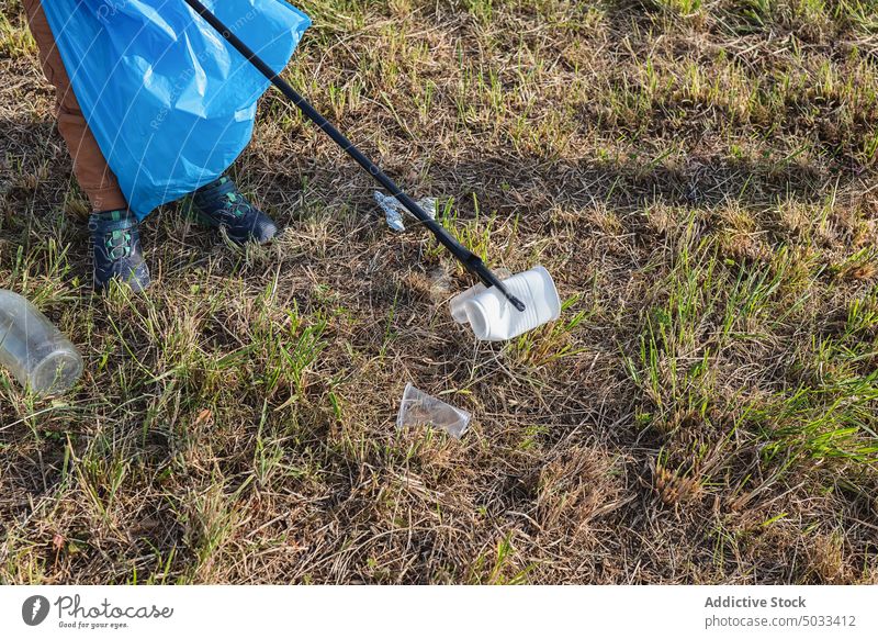 Erntehelfer pflückt Plastik mit einem Stock auf einer Wiese Freiwilliger Plastikbecher abholen pflücken Müll Sauberkeit Kunststoff verschmutzen Abfall kleben