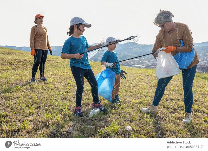 Freiwillige Helfer sammeln Müll auf einer Wiese in der Natur Freiwilliger Umwelt abholen Tasche Frau Großmutter Kinder Ökologie Landschaft Abfall verschmutzen