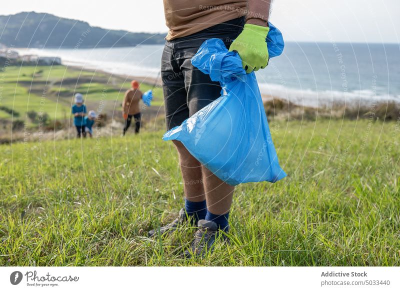 Unbekannter Mann steht mit Müllsack in der Natur Freiwilliger abholen Tasche Abfall Umwelt Ökologie tagsüber Behälter Sonne Aktivist wiederverwerten Sauberkeit