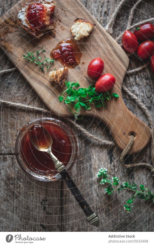 Tomatenkonfitüre und Schneidebrett auf Holztisch Marmelade Kraut Brot Löffel hölzern Tisch Küche selbstgemacht Ernährung organisch Glas Lebensmittel frisch