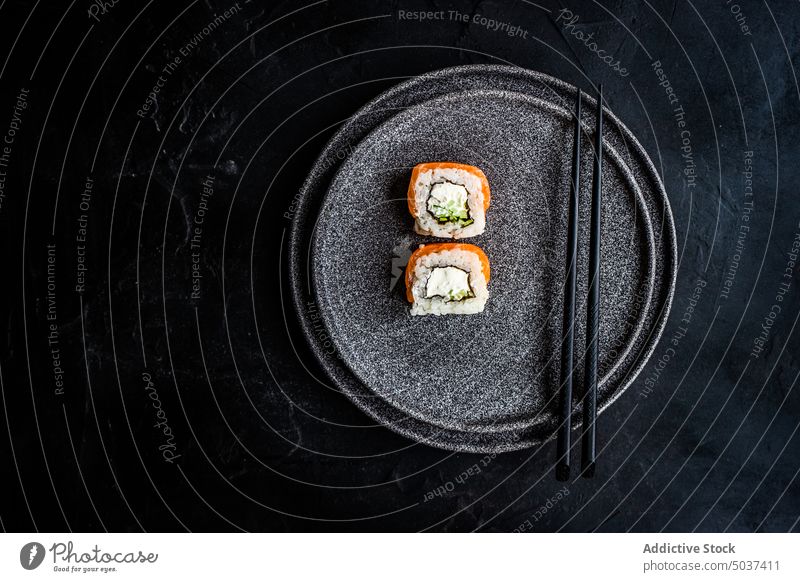 Schwarzer Steinteller mit asiatischen Rollen Sushi schwarz Kalifornische Walze Essstäbchen dunkel essen Fisch Lebensmittel Japan Japanisch Mahlzeit Minimalismus