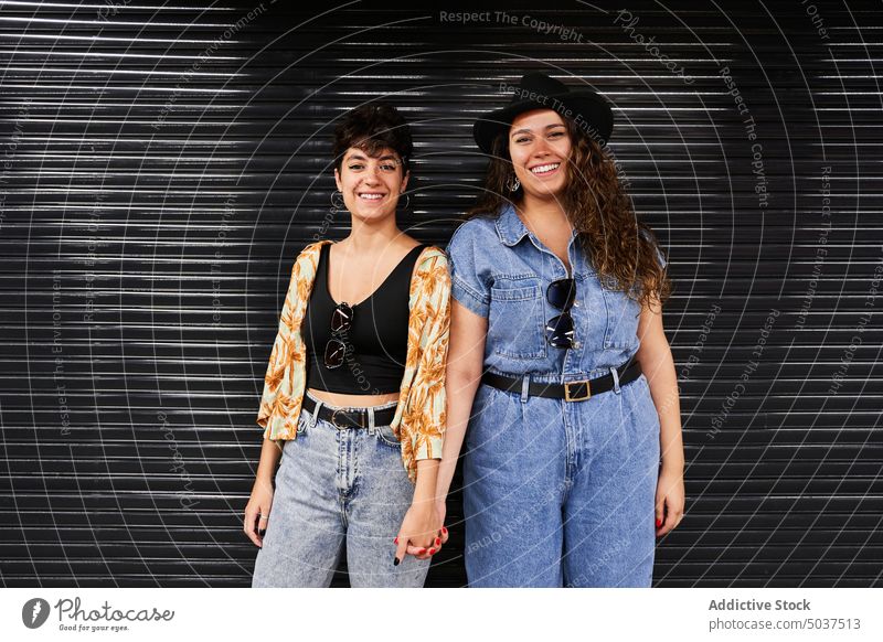 Lesbisches Paar vor schwarzer Wand Frauen Lächeln Händchenhalten Zusammensein Freundin Stil urban Wochenende Termin & Datum Madrid Spanien jung Straße froh