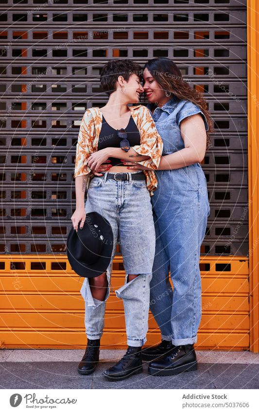 Verliebte Freundinnen umarmen sich auf der Straße Frauen Paar Umarmung Liebe Lächeln Wand Berührungsnase Glück lesbisch Madrid Spanien jung Zusammensein