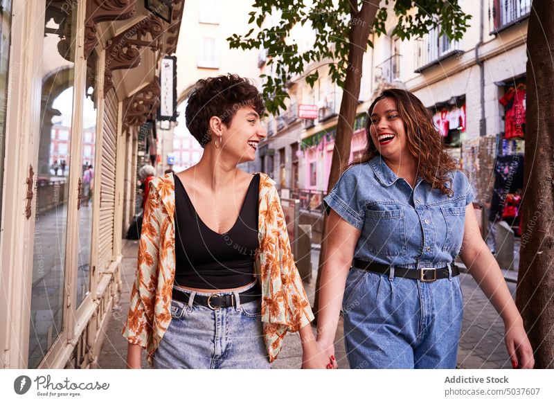 Lesbisches Paar schlendert auf der Straße Frauen Spaziergang Zusammensein Händchenhalten Lächeln Stil lesbisch Freundin Madrid Spanien jung Straßenbelag Glück