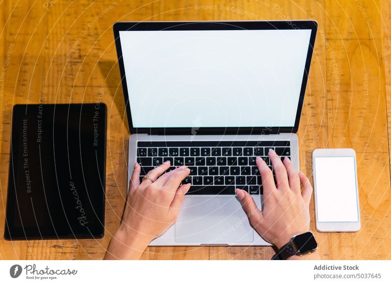 Crop-Frau benutzt Geräte im Restaurant Geschäftsfrau Laptop benutzend Tisch leerer Bildschirm Tablette Rotwein Smartphone abgelegen schwarzer Bildschirm