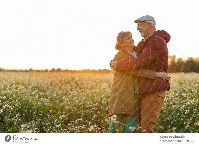 Älteres Paar auf einem Feld im Herbst bei Sonnenuntergang laufen Ausflug Rucksack Seniorenpaar Frau Zwei Personen Mann reif Zusammensein alt Menschen