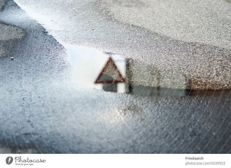 Spiegelung eines Verkehrszeichens in einer Pfütze im Asphalt Pfützenspiegelung Reflexion & Spiegelung nach dem regen Straße vorfahrt gewähren Wasser nass Regen