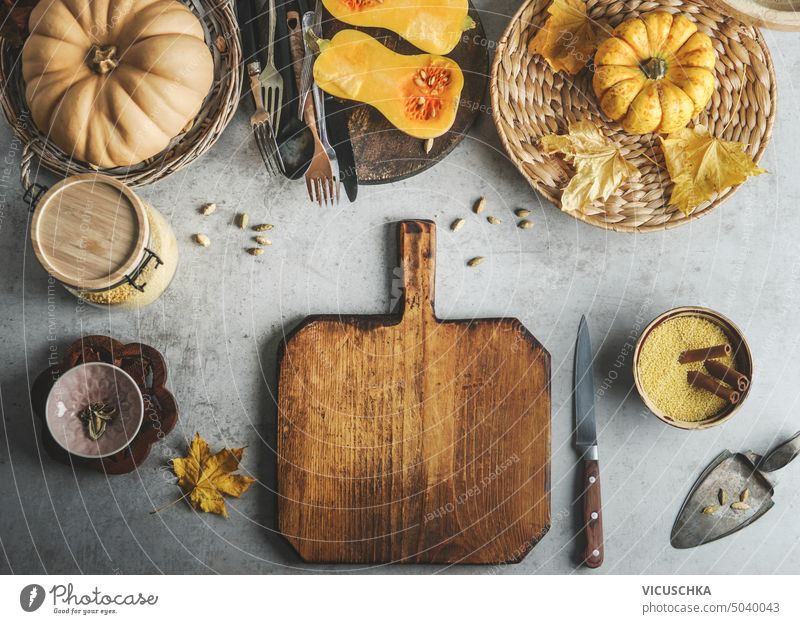 Lebensmittel Hintergrund mit Kürbissen, Schneidebrett, Messer und andere Gewürze und Zutaten, Ansicht von oben. Rahmen. Saisonale Herbst Kochen Konzept