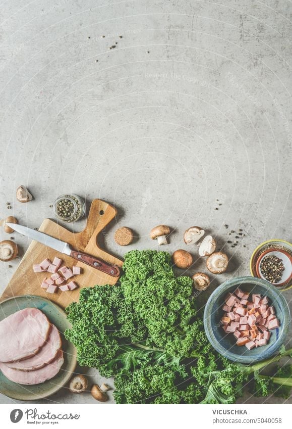Grünkohl kochen Hintergrund mit frischen Grünkohlblättern, geräuchertem Schweinefleisch und Pilzen, Ansicht von oben, Rahmen Kale Essen zubereiten Fleisch