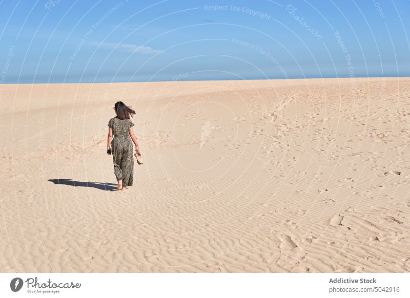 Anonyme Frau, die an einem sonnigen Tag auf einer Sanddüne spazieren geht Spaziergang Strand Düne Feiertag Tourist Natur Meeresufer Urlaub erkunden wüst