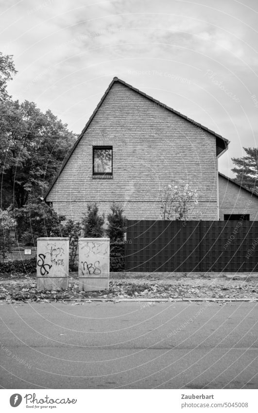 Asymmetrische Fassade eines Einfamilienhauses mit zwei Sicherungskästen in schwarz-weiß Wohnhaus asymmetrisch sachlich Sachlichkeit Wand Fenster Dach