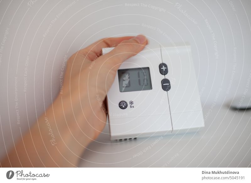 Die Hand hält ein Thermometer, das die Temperatur im Raum anzeigt. Extrem heiße Temperatur auf dem Bildschirm des Heimthermostats. Auswirkungen des Klimawandels mit extremer Hitze.