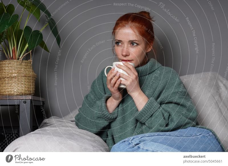 Frau entspannt sich zu Hause und trinkt Kaffee entspannend trinken Tasse Tagträumen Denken Armsessel echte Menschen besinnlich Sitzen im Innenbereich Dame