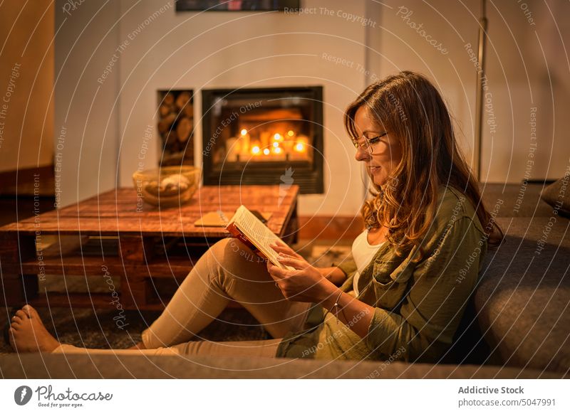Hispanische Frau liest abends in einem Buch lesen Sofa Abend Wohnzimmer Wochenende Lächeln interessant Etage reif Lebensmitte hispanisch ethnisch Hobby heiter