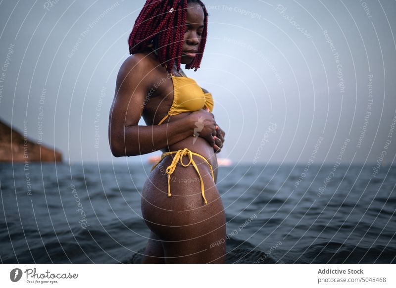 Schwarze Frau im Bikini im Meer stehend MEER Strand Urlaub sorgenfrei Tourist Natur Feiertag genießen Badebekleidung Wasser schlank Freiheit reisen Dame Ausflug