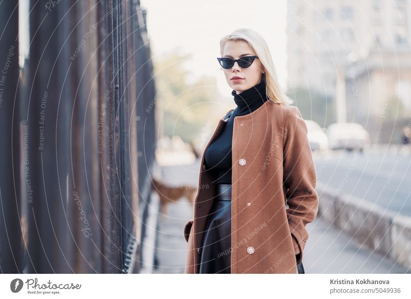 Porträt der jungen blonden Geschäftsfrau im Herbst Stadt. Mädchen haben stilvollen Look, Sonnenbrille und Nasenpiercing. Lady zu Fuß auf der Straße allein. Mode-Konzept