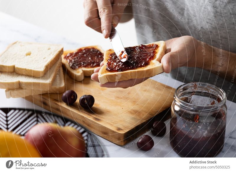 Erntehelfer bei der Zubereitung von Toasts mit Kirschmarmelade Mann vorbereiten Frühstück Aufstrich Kirsche Marmelade Zuprosten Messer Schliere Lebensmittel