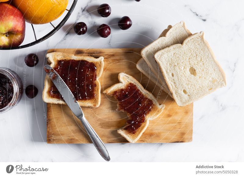 Leckere Toasts mit Marmelade auf dem Schneidebrett Lebensmittel Frühstück lecker Zuprosten Beeren Kirsche süß Messer frisch geschmackvoll dienen appetitlich