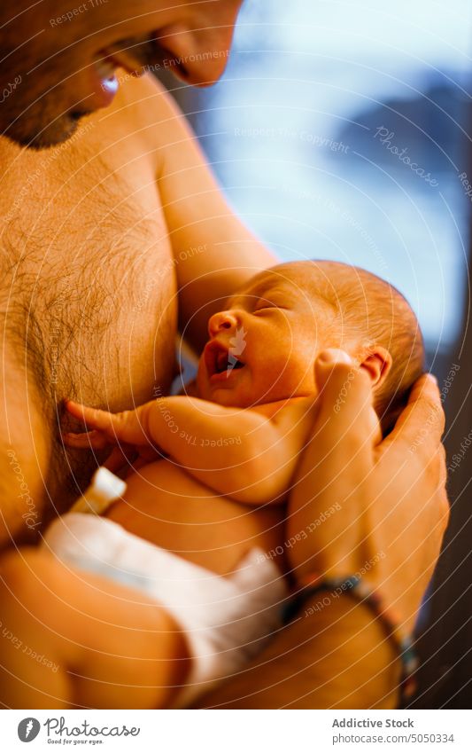 Mann ohne Hemd hält neugeborenes Baby im Arm Vater Säugling Liebe Pflege sanft Elternschaft Halt Glück heimwärts Windel Angebot Kindheit Zusammensein Bonden