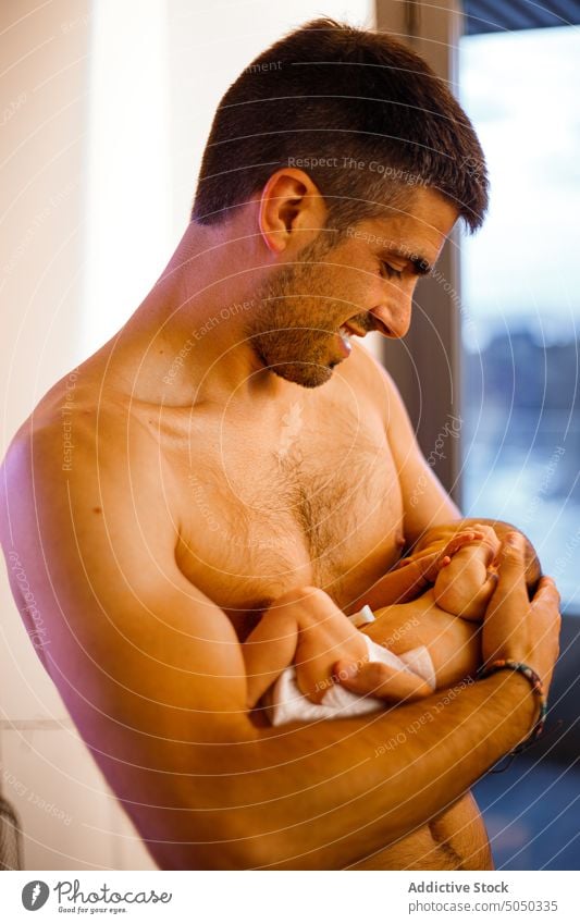 Mann ohne Hemd hält neugeborenes Baby im Arm Vater Säugling Liebe Pflege sanft Elternschaft Halt Glück heimwärts Windel Angebot Kindheit Zusammensein Bonden