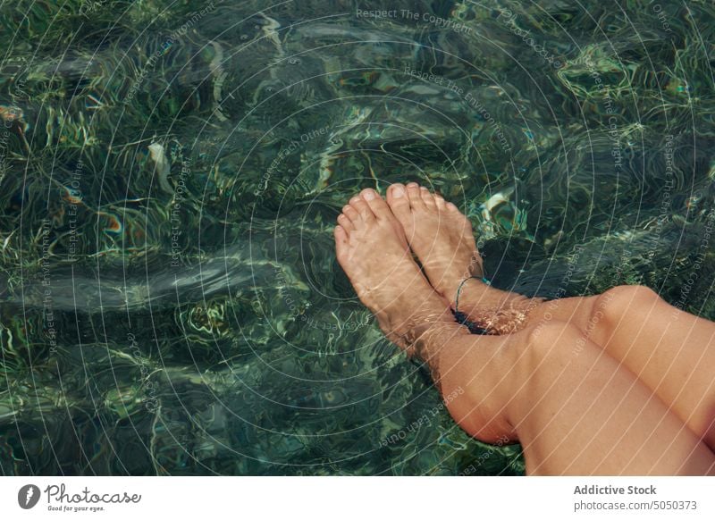 Anonyme entspannte Frau mit baumelnden Beinen im Wasser von der Seebrücke Sommer Pier tropisch ruhen sorgenfrei sich[Akk] entspannen schäbig friedlich