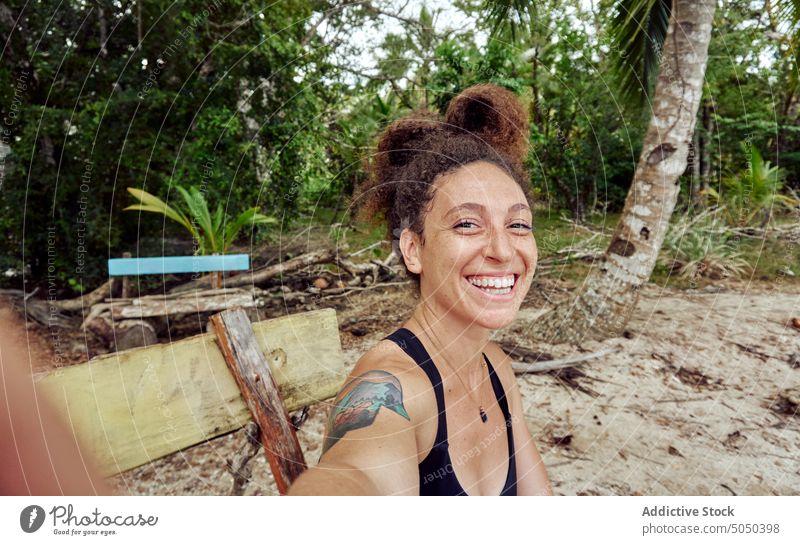 Glückliche Frau nimmt Selfie auf Bank auf tropischen Ufer heiter Strand Meeresufer Feiertag Sommer exotisch Lächeln Resort Handfläche ethnisch hispanisch