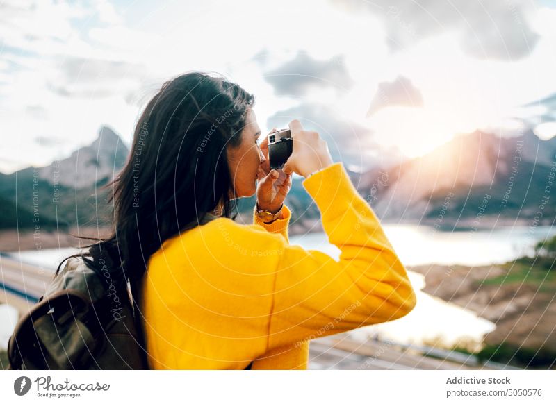 Frau mit Rucksack beim Fotografieren des malerischen Hochlands Reisender fotografieren Fotoapparat Berge u. Gebirge See Natur reisen Tourist Gerät Gedächtnis