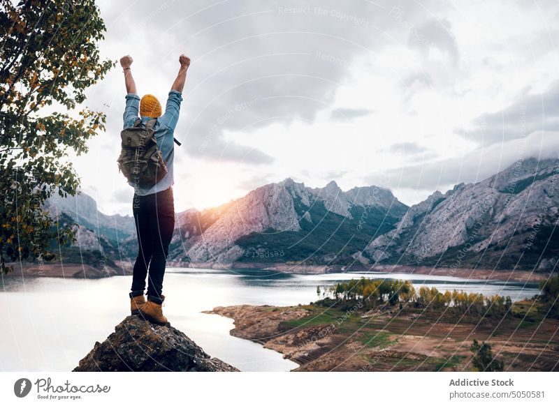 Reisender steht auf einer Felsformation in der Nähe eines Sees Backpacker Tourist Fäuste hoch erhobene Hände Berge u. Gebirge Gipfel erreichen beobachten