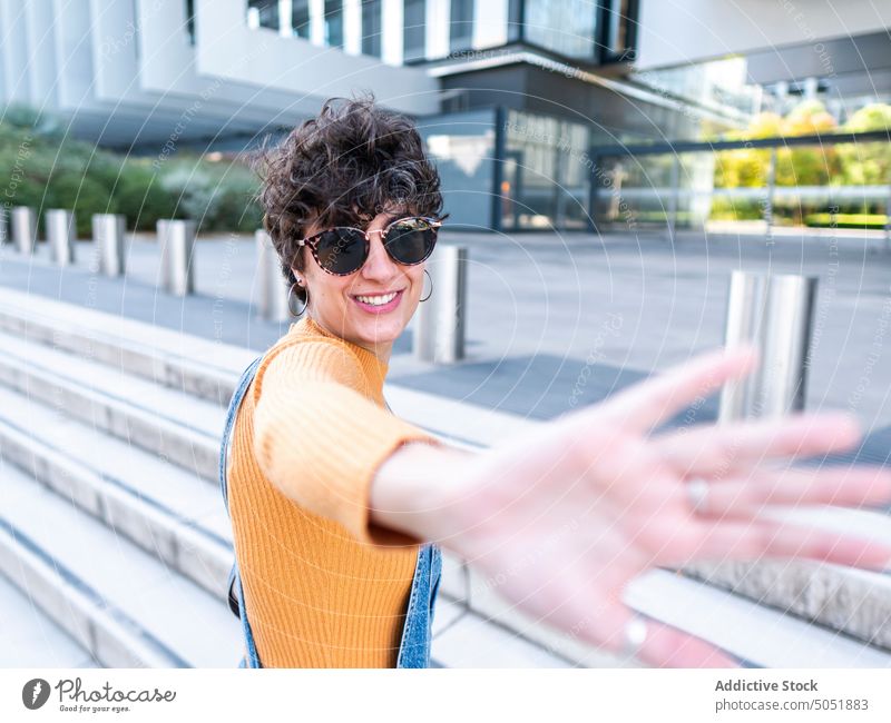 Fröhliche Frau genießt die Sonne auf der Straße Gebäude Sommer sorgenfrei genießen heiter Veranda Freizeit urban Stil Großstadt Lächeln positiv brünett Treppe