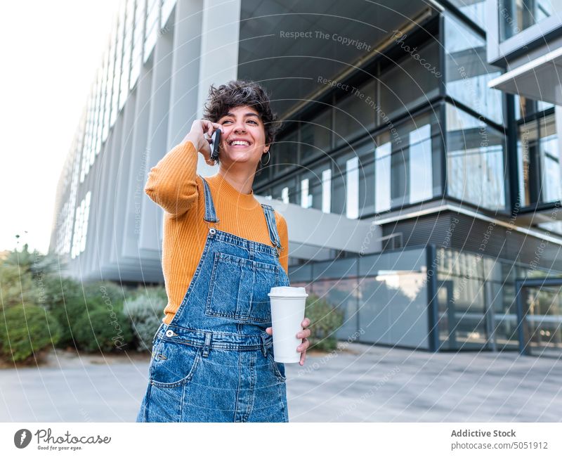 Frau mit Kaffee zum Mitnehmen benutzt Mobiltelefon auf der Straße Smartphone benutzend Browsen Funktelefon Imbissbude Telefon Spaziergang Sommer urban Stil