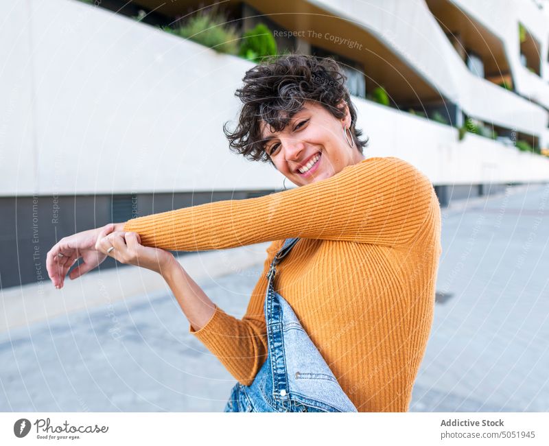 Fröhliche Frau vor einem städtischen Gebäude Großstadt urban Architektur Stil Straße Jeansstoff Konstruktion Kurze Haare Frisur kreativ nachdenken gesamt stehen