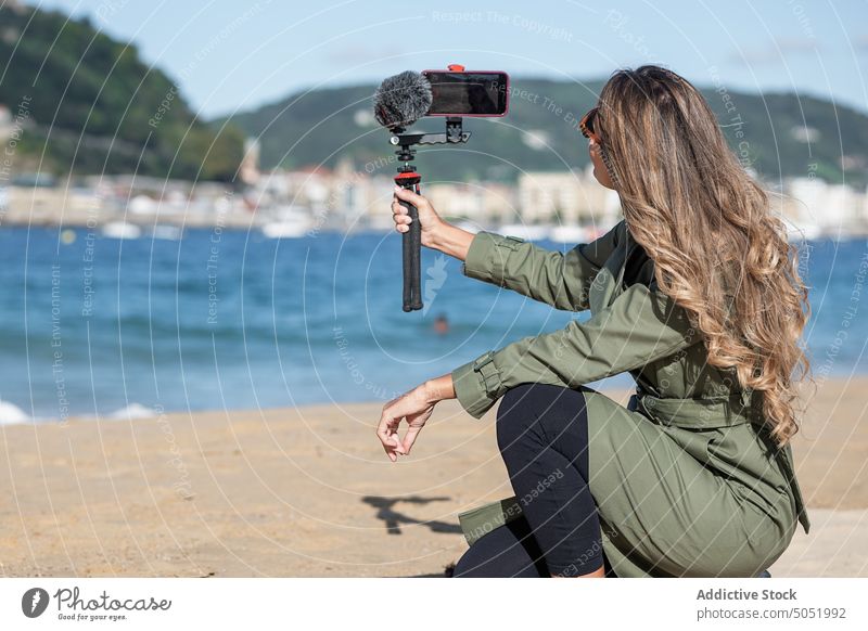 Frau, die am Strand eine Kamera mit Mikrofon aufnimmt Aufzeichnen Video vlog fotografieren Fotokamera Gerät MEER Großstadt Vlogger Selfie Influencer Fotoapparat