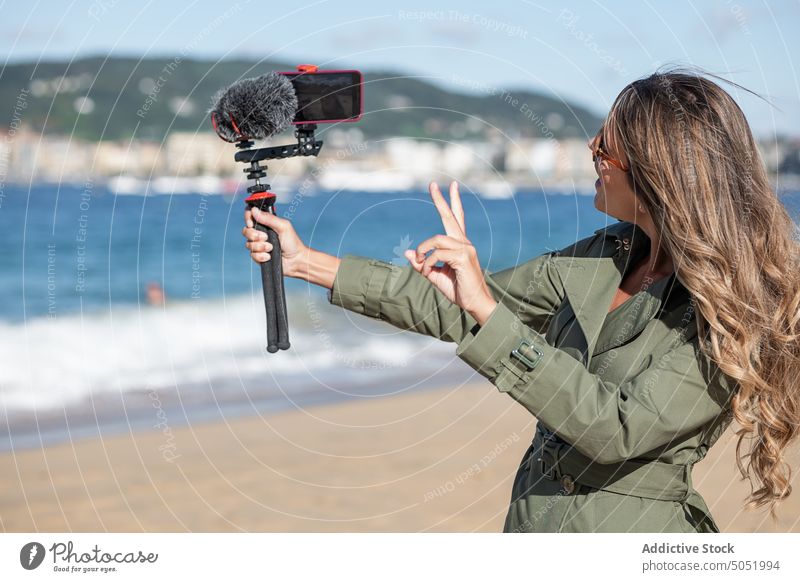 Frau, die am Strand eine Kamera mit Mikrofon aufnimmt Aufzeichnen Video vlog fotografieren Fotokamera Gerät MEER Großstadt Vlogger Selfie Influencer Fotoapparat