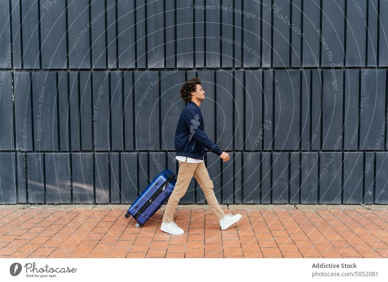 Schwarzer Mann mit Gepäck auf der Straße Tourist Spaziergang Koffer Wand Straßenbelag Gebäude urban ziehen männlich schwarz Afroamerikaner ethnisch modern
