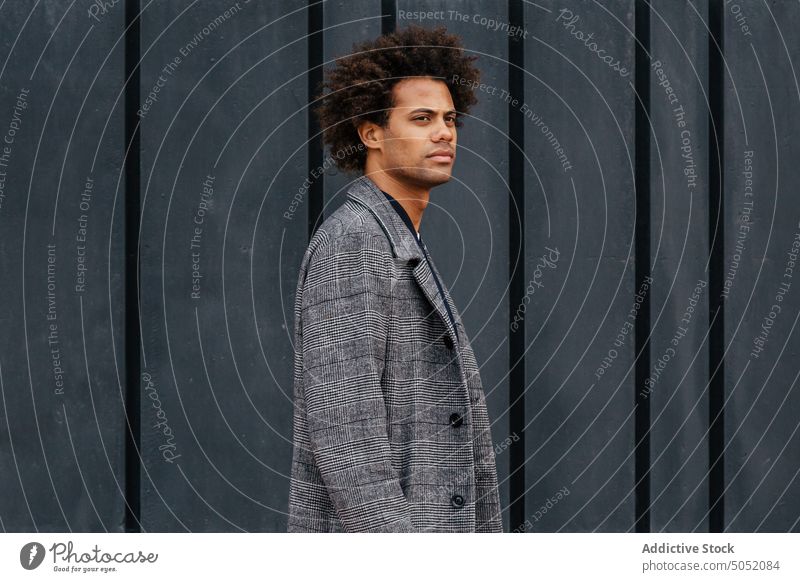 Stilvoller schwarzer Mann auf der Straße Wand smart lässig Jacke krause Haare ernst Vorschein modern männlich jung Afroamerikaner ethnisch Gebäude Stoff