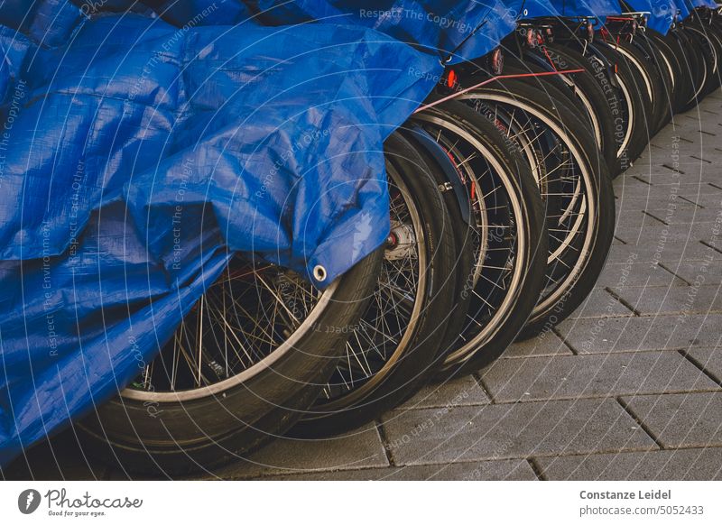 Ein Reihe von Fahrrädern  unter einer blauen Abdeckplane. Fahrradfahren Verkehr Mobilität Verkehrsmittel Straßenverkehr Stadt Freizeit & Hobby Fahrradtour