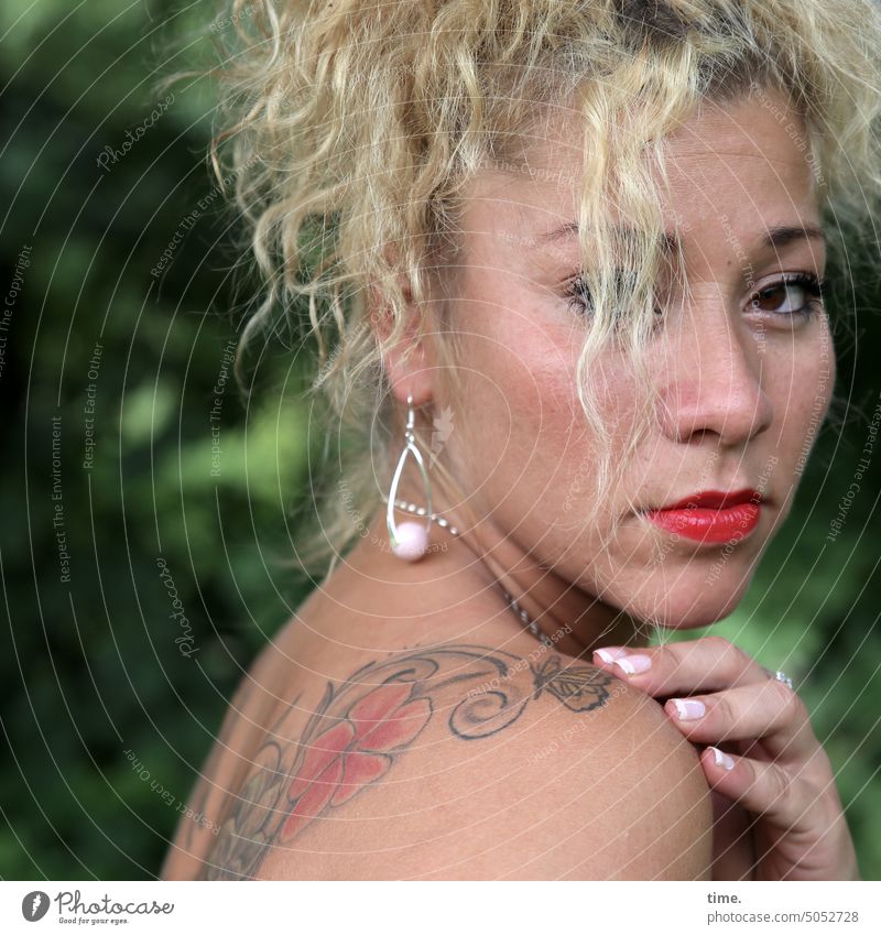 Frau mit Tattoo feminin Ohrringe langhaarig blond Blick beobachten Locken warten ruhig Gelassenheit Traurigkeit Sorge Müdigkeit Respekt Konzentration