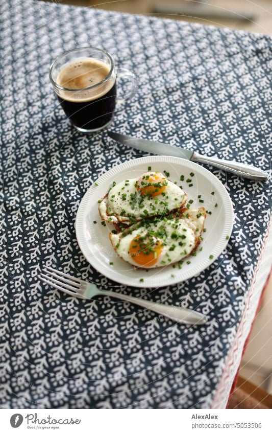 Gedeckter Frühstückstisch - zwei Spiegeleier auf Brot mit auf einem weißen Teller mit Besteck und gläserner Kaffeetasse Essen Mahlzeit Spiegeleiner auf Brot