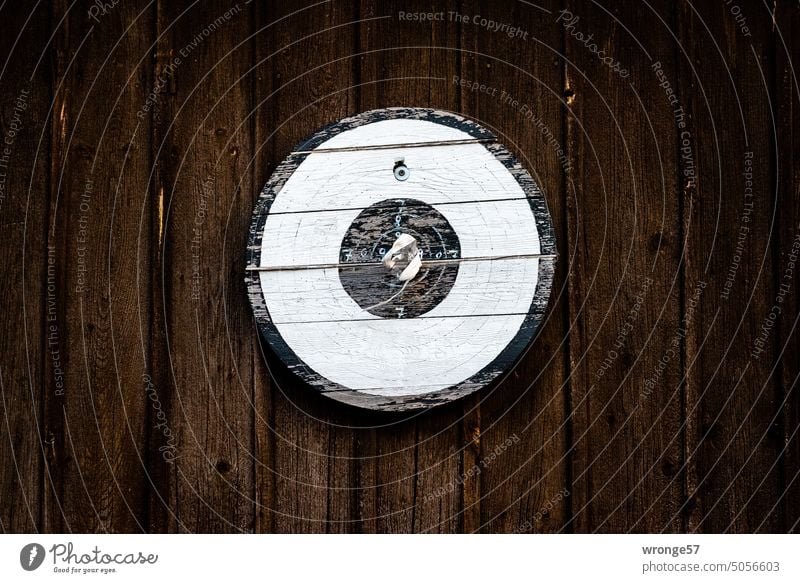 Ältere verwitterte Zielscheibe hängt an einer braunen Bretterwand alt alt und verwittert Holzscheibe hölzerne Zielscheibe Schützenkönig Schützenverein Haus