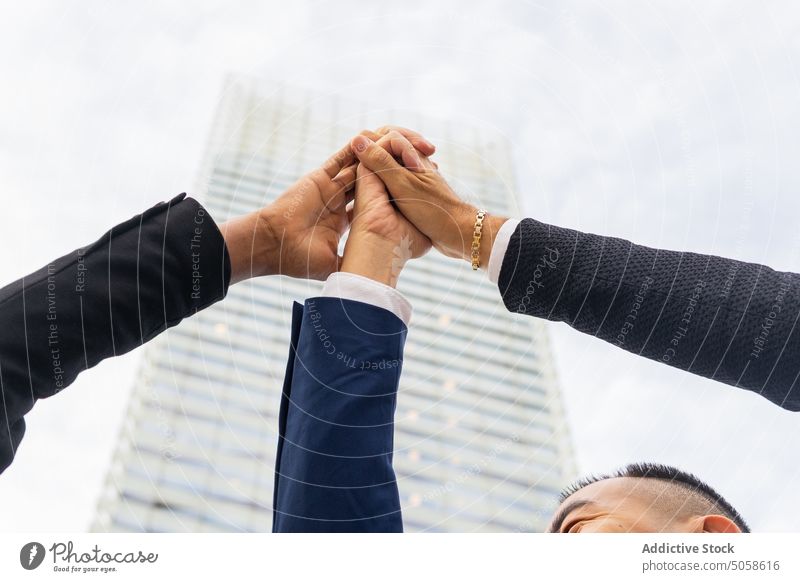 Anonyme Geschäftsleute stapeln die erhobenen Hände auf der Straße Mitarbeiterin Kollege Hände stapeln Arme hochgezogen Wolkenkratzer Team zusammenarbeiten