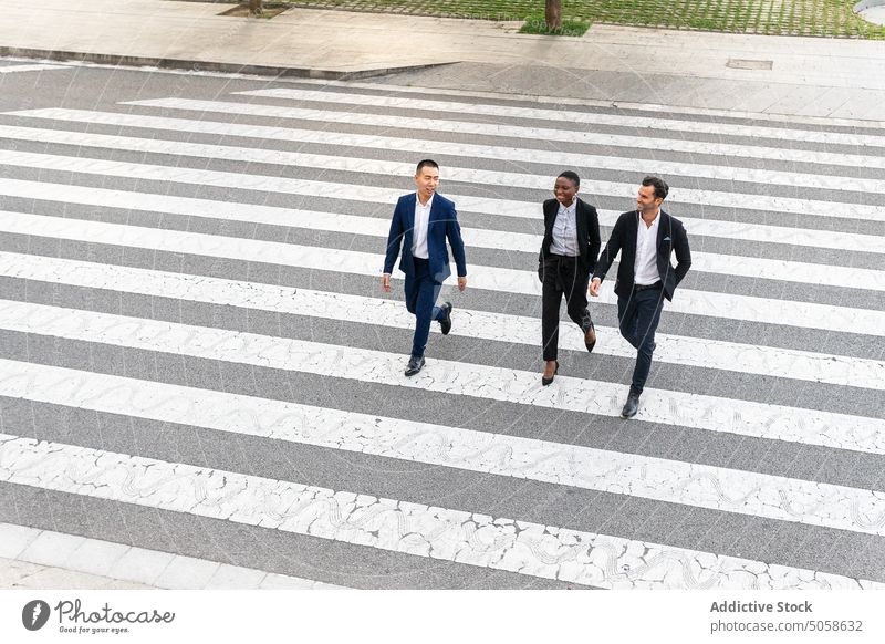 Multiethnische Mitarbeiter gehen auf dem Zebrastreifen Geschäftsleute Mitarbeiterin Kollege heiter Straße Fußgänger Spaziergang Talkrunde Menschen Kommunizieren
