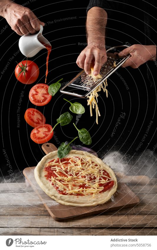 Crop-Köche kochen Pizza mit Tomaten im dunklen Studio Küchenchef Käse Gitter margherita Basilikum Rezept Koch eingießen fallen Marinara Bestandteil