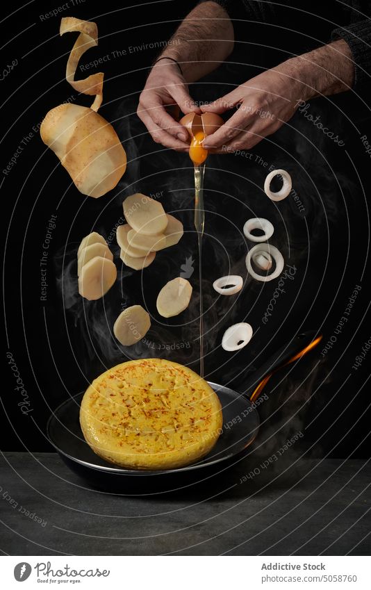 Unkenntlicher Koch, der ein Omelett auf dunklem Hintergrund zubereitet Küchenchef Bestandteil Kartoffel Rezept Ei fallen Zwiebel kulinarisch vorbereiten Pause