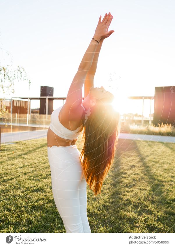 Schlanke Frau mit erhobenen Armen im Park Sportlerin betende Hände Yoga Asana Namaste Dehnung Training Aufwärmen passen Gesundheit Wellness Sportbekleidung