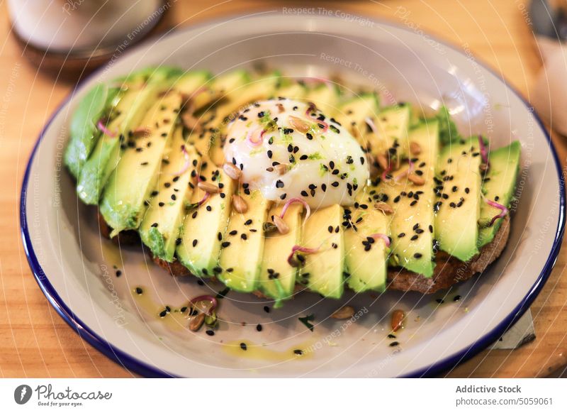 Leckerer Toast mit Avocado und pochiertem Ei Lebensmittel Zuprosten dienen Frühstück Mahlzeit gesunde Ernährung Chia appetitlich geschmackvoll Samen Gesundheit