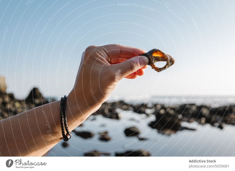 Crop Frau zeigt Muschel am Meer Tourist zeigen MEER Sonnenaufgang Wolkenloser Himmel Morgen Sommer Golfloch Alkolea-Strand mutriku gipuzkoa Spanien ruhig