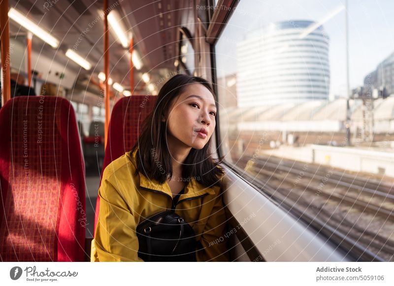 Asiatische Frau fährt Zug in der Stadt Mitfahrgelegenheit Fenster Passagier reisen Großstadt Arbeitsweg tagsüber Öffentlich London England Großbritannien