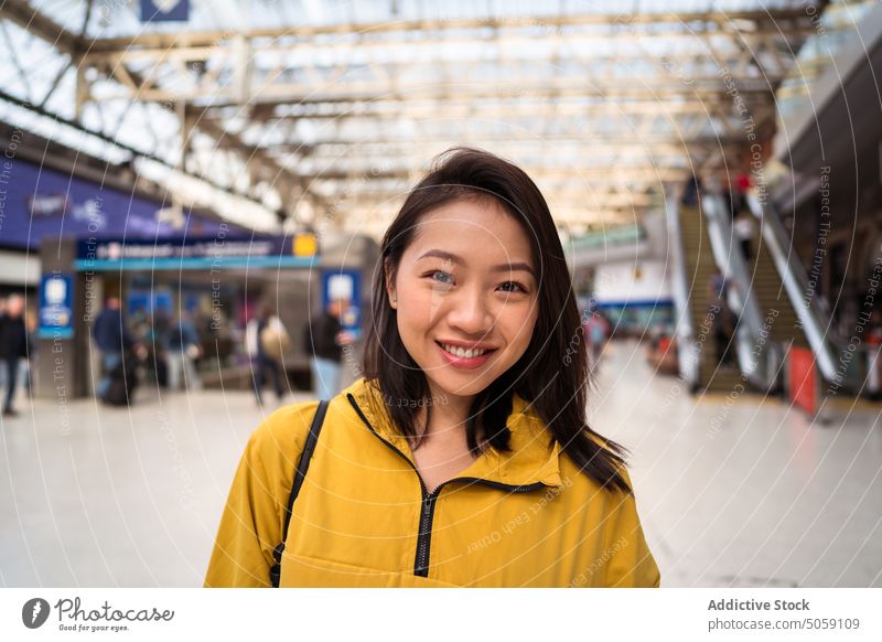 Fröhlicher asiatischer Reisender am Bahnhof Frau Lächeln Glück Arbeitsweg Passagier Wochenende Transit Porträt London England vereinigtes königreich