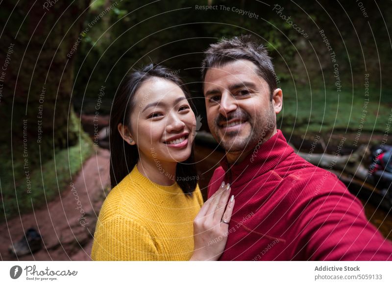 Glückliches vielfältiges Paar nimmt Selfie im Park Lächeln Freund Freundin heiter Wald reisen Urlaub Schottland Natur Zusammensein Partnerschaft asiatisch