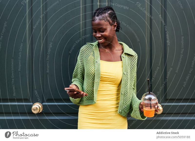 Stilvolle junge ethnische weibliche Millennials verwenden Smartphone auf der Straße Frau Nachricht selbstbewusst trinken Imbissbude benutzend cool Getränk